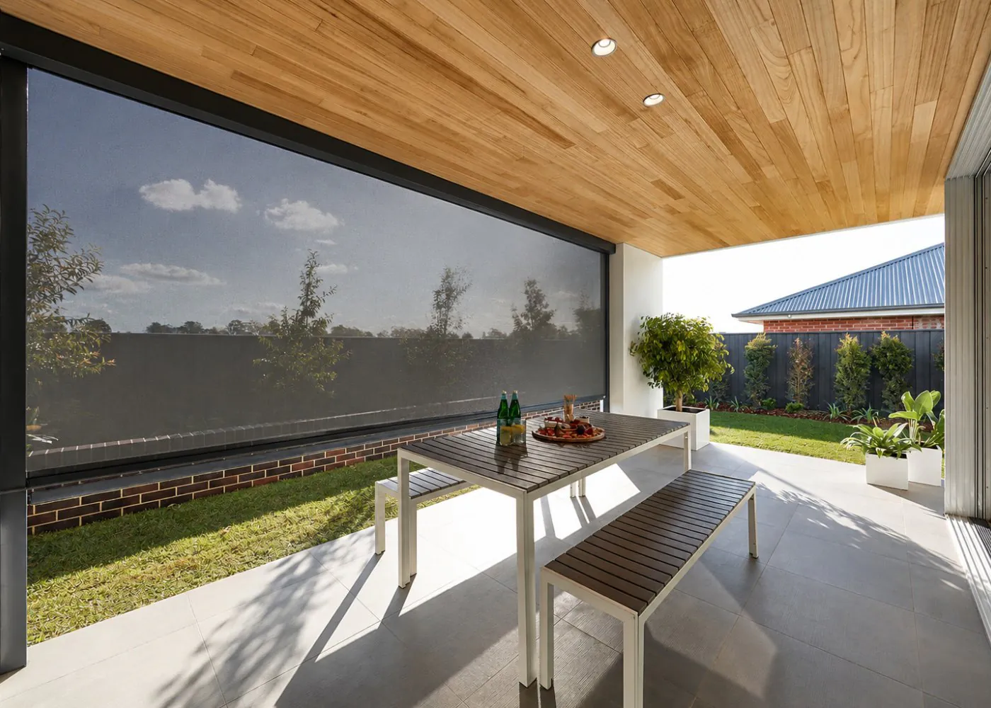 A motorized zip-track outdoor screen shading a patio