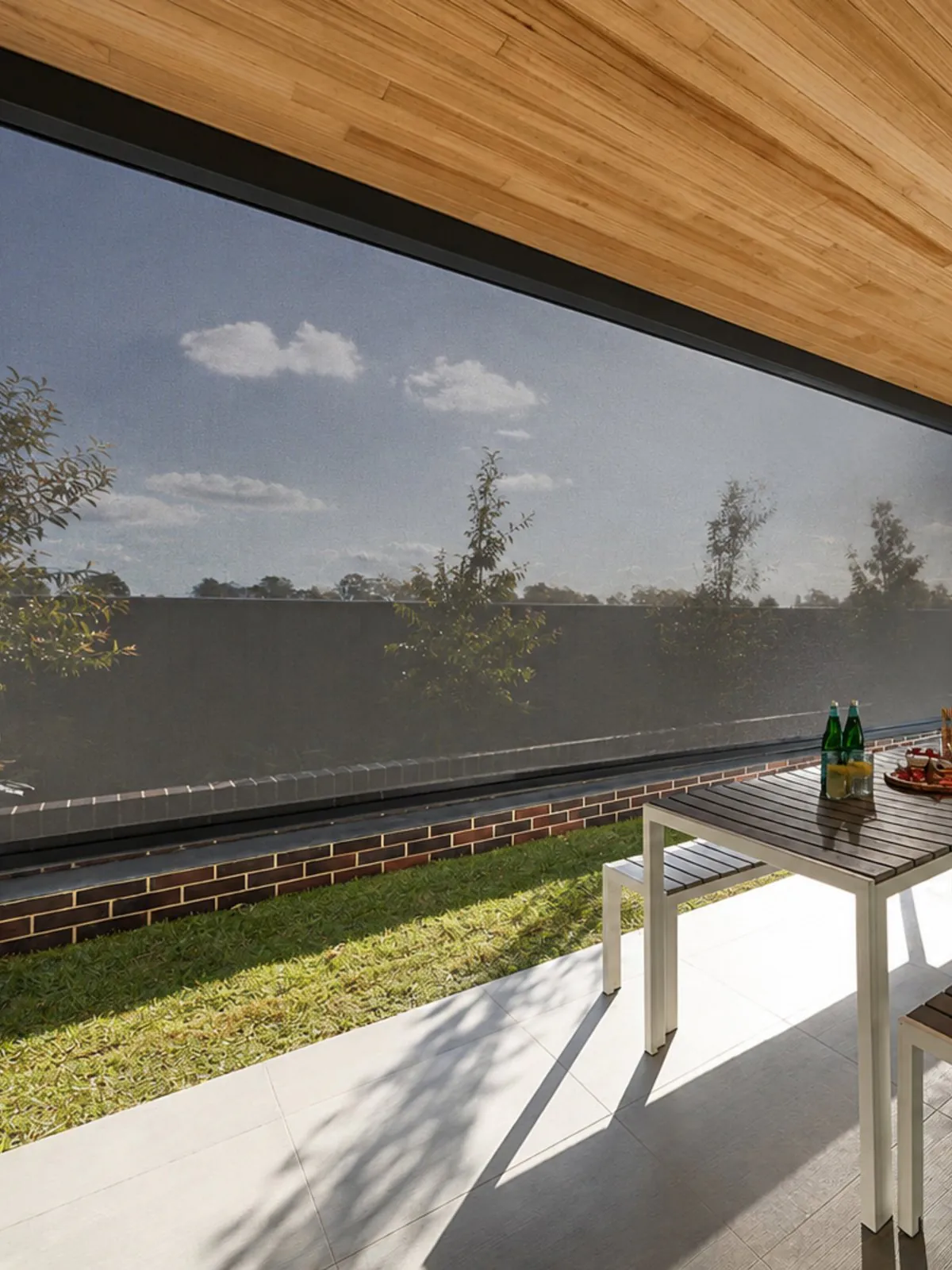 A heavy-duty roll-down outdoor blind enclosing a covered patio